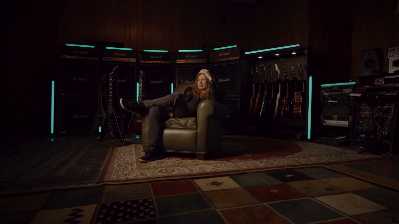 Dave Mustaine sitting in a studio surrounded by guitars and amplifiers