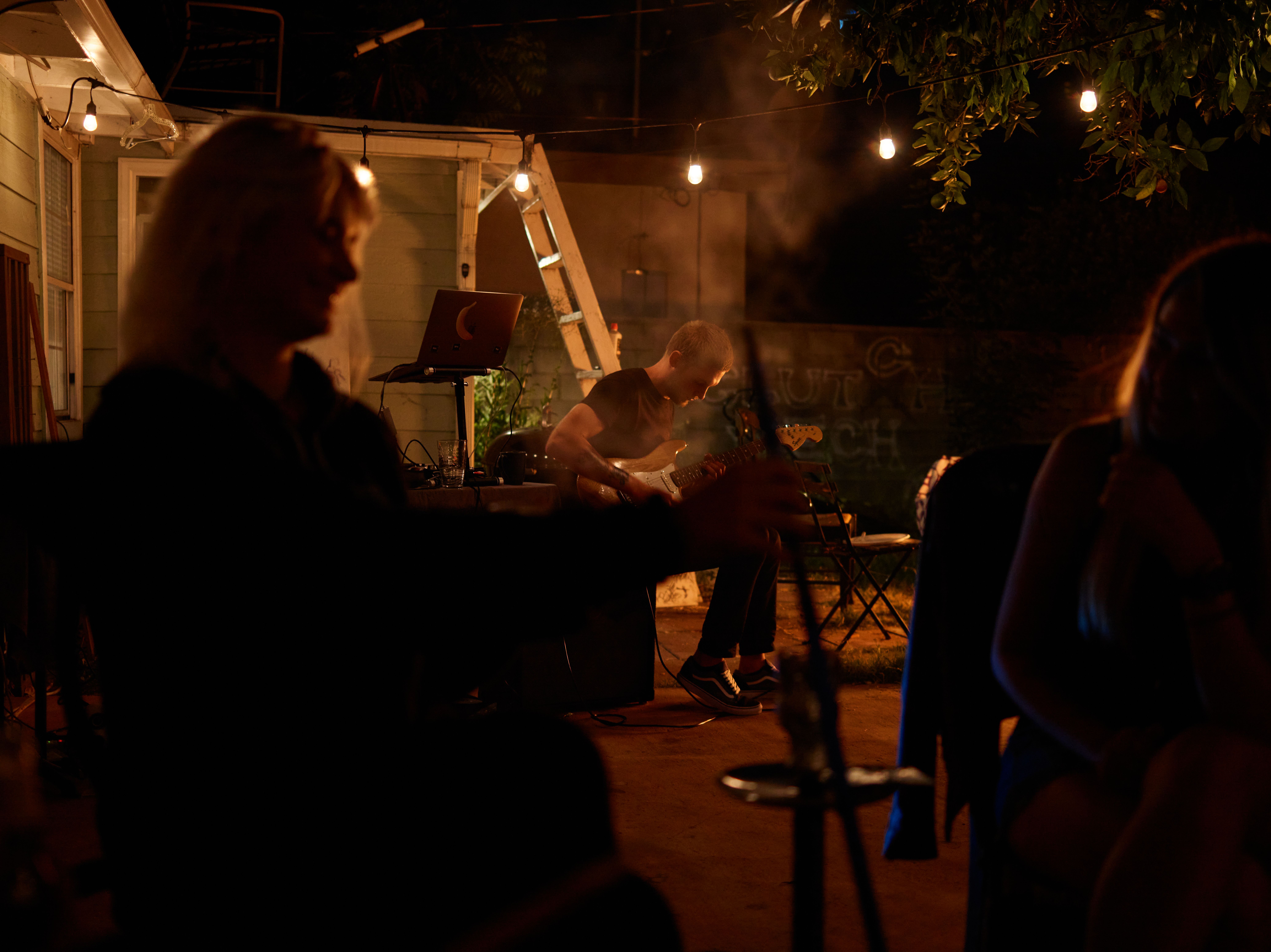 Relaxed nighttime backyard jam session with guitar and casual ambiance