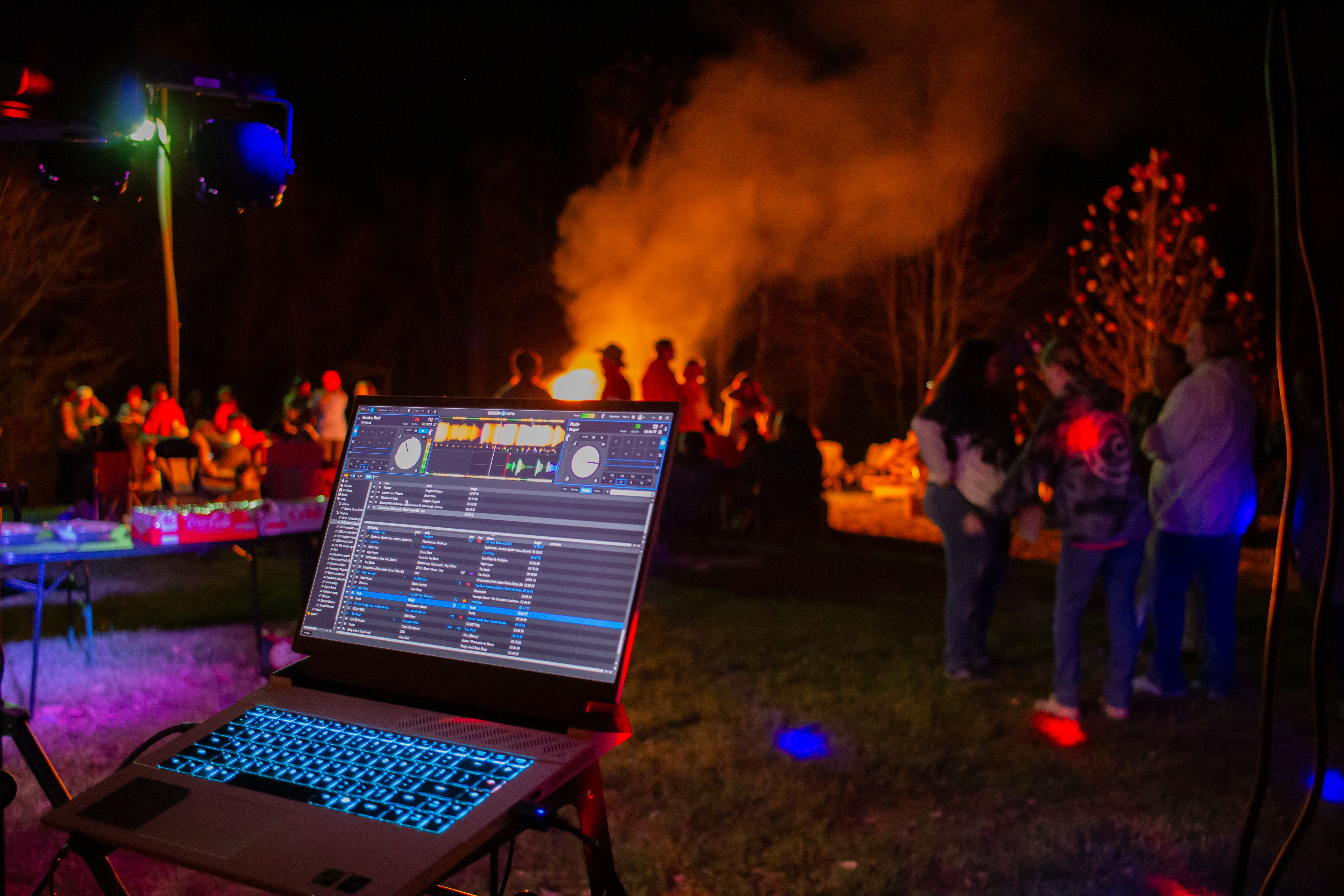 Outdoor night party with a DJ setup and bonfire