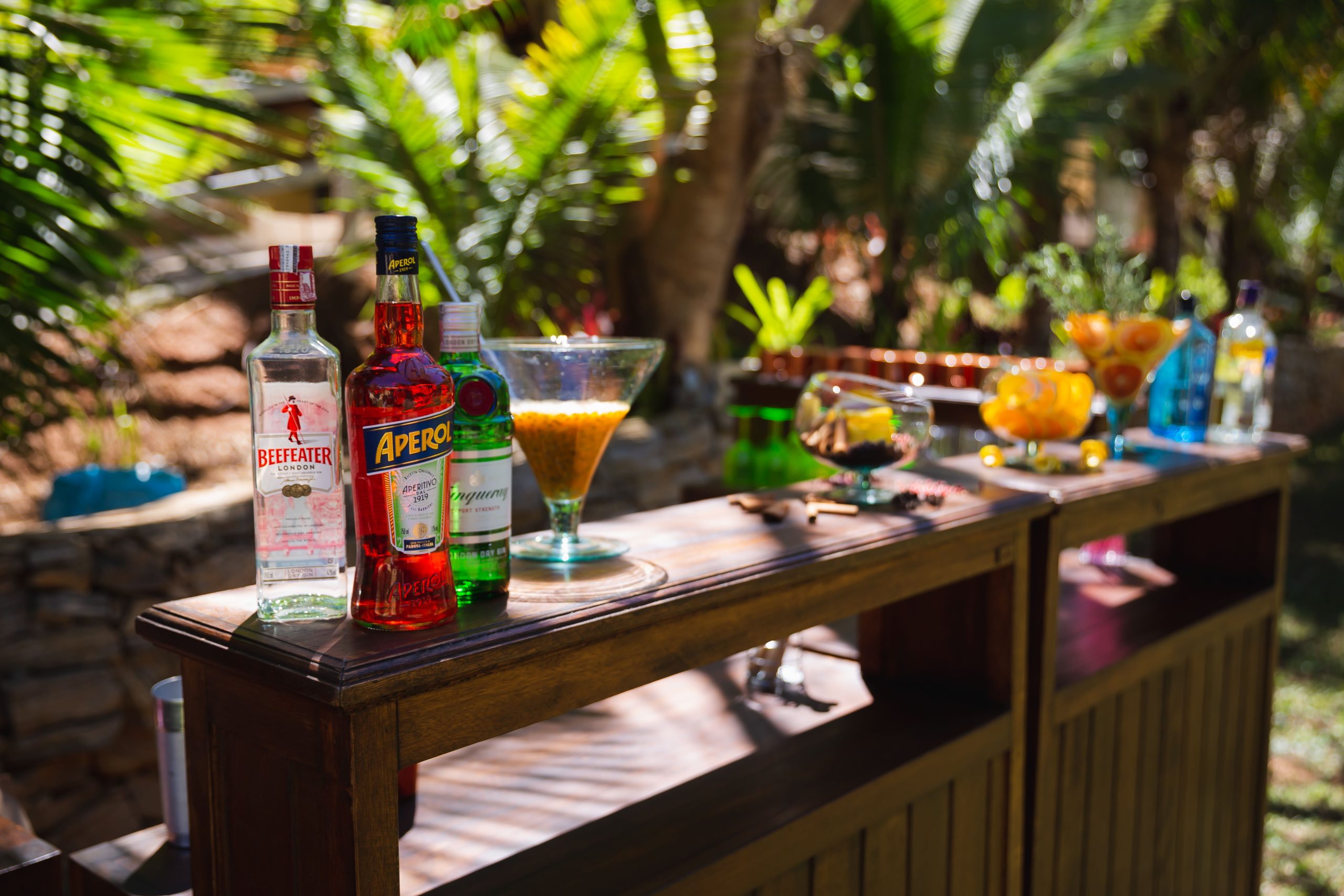 Bright outdoor bar scene with cocktails and spirits on a wooden counter